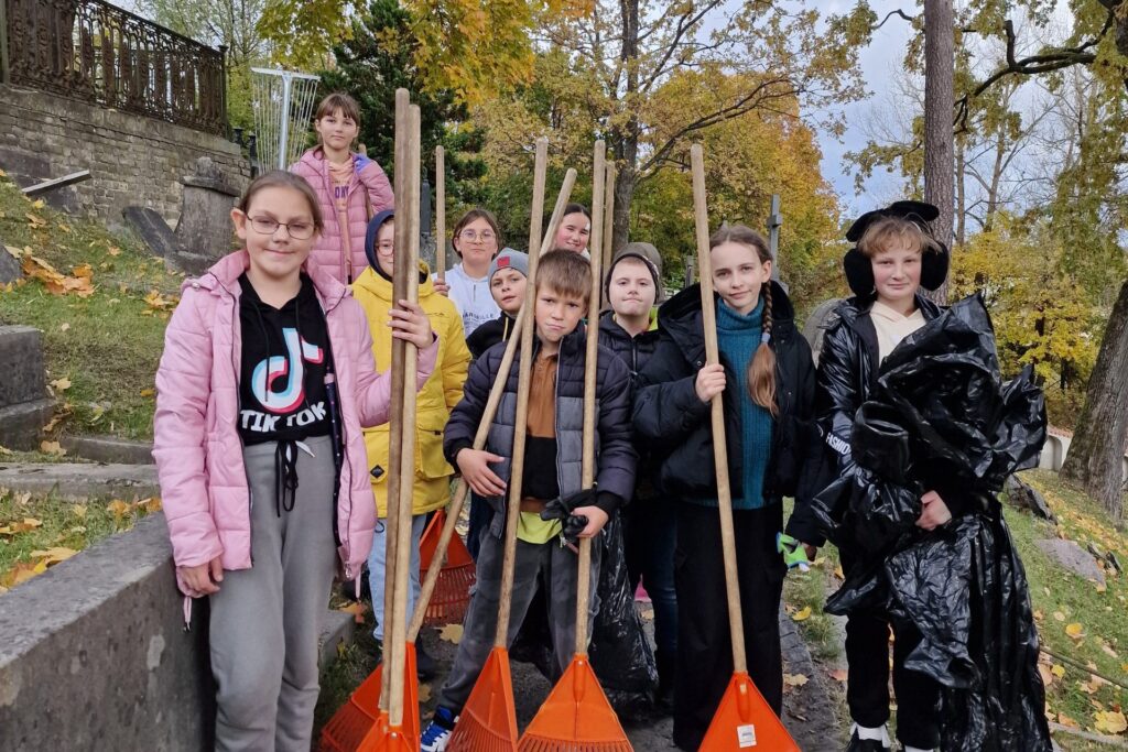 Uczniowie w czasie grabienia liści na cmentarzu. Źródło: https://www.slovackio.vilniausr.lm.lt/?p=30714&fbclid=IwY2xjawGUZ09leHRuA2FlbQIxMAABHQScwFI0-irxQRJSznrRVZeGZI_KqErOW1jK0Ot1v9gNy8-QIVygTVphXg_aem_-7q63I_FIlMT5O2mdLMKXA&lang=pl