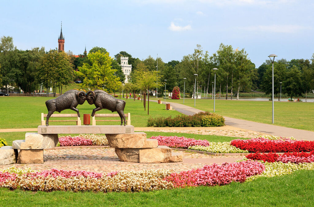 Centralna część parku w Druskienikach, w tle widać kościół pw. Matki Boskiej Szkaplerznej oraz Willę Kieronowskich. Źródło: Juliux, CC BY-SA 3.0 <https://creativecommons.org/licenses/by-sa/3.0>, via Wikimedia Commons